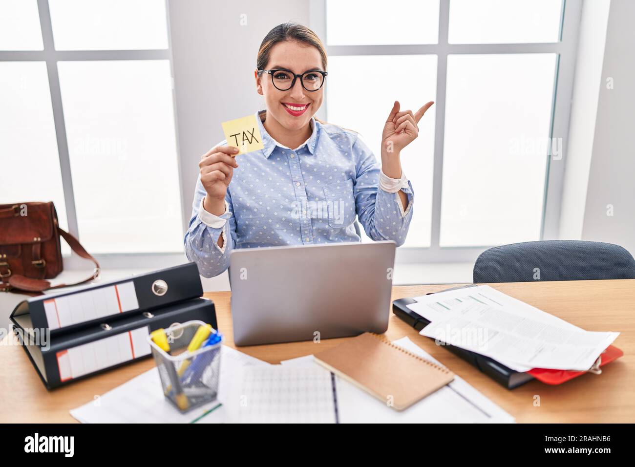 Young hispanic business woman at the office calculating taxes smiling ...