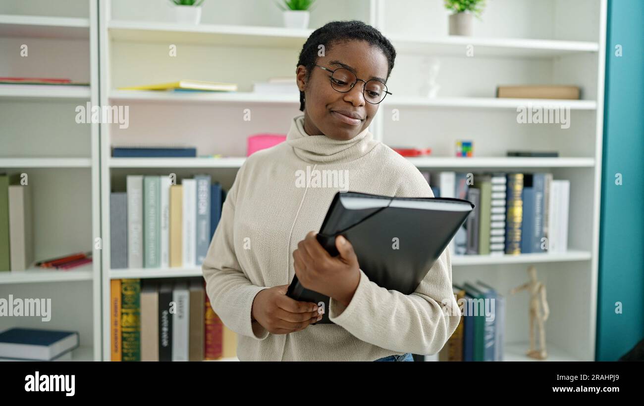 African american woman student smiling confident holding binder at ...
