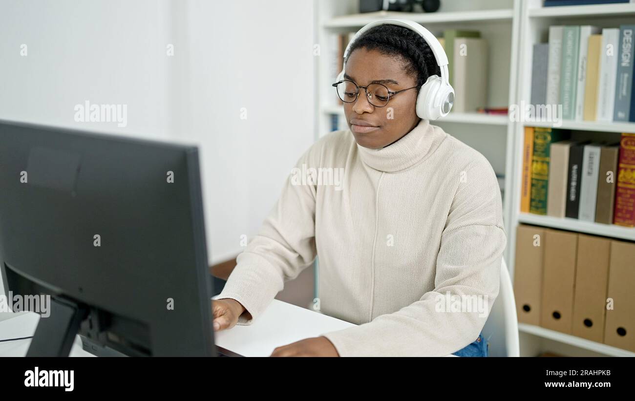 African american woman student using computer and headphones studying ...