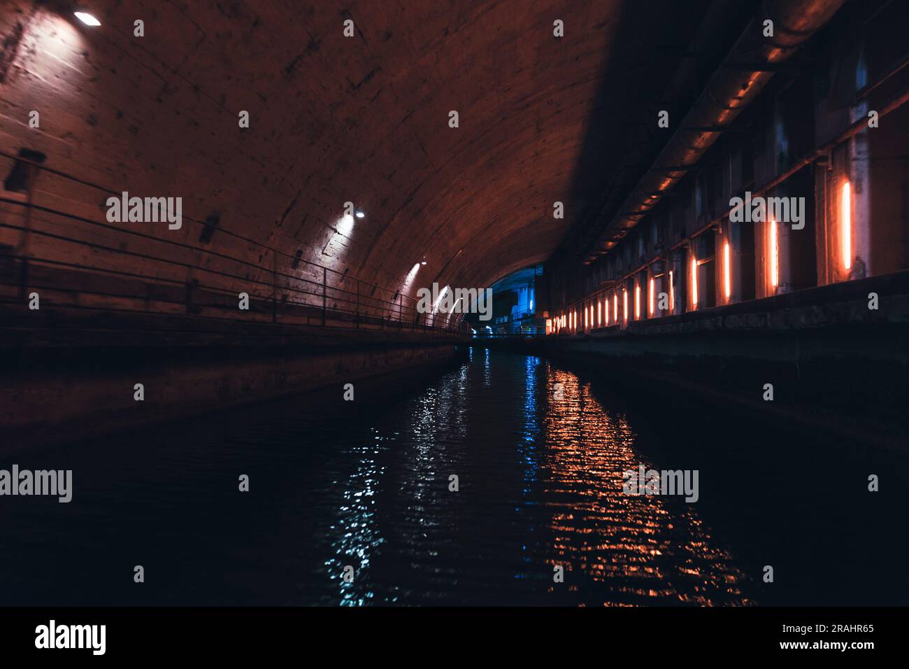 Industrial concrete tunnel perspective with neon lights illumination. Abandoned underground submarine base from USSR period located in Balaklava, Crim Stock Photo