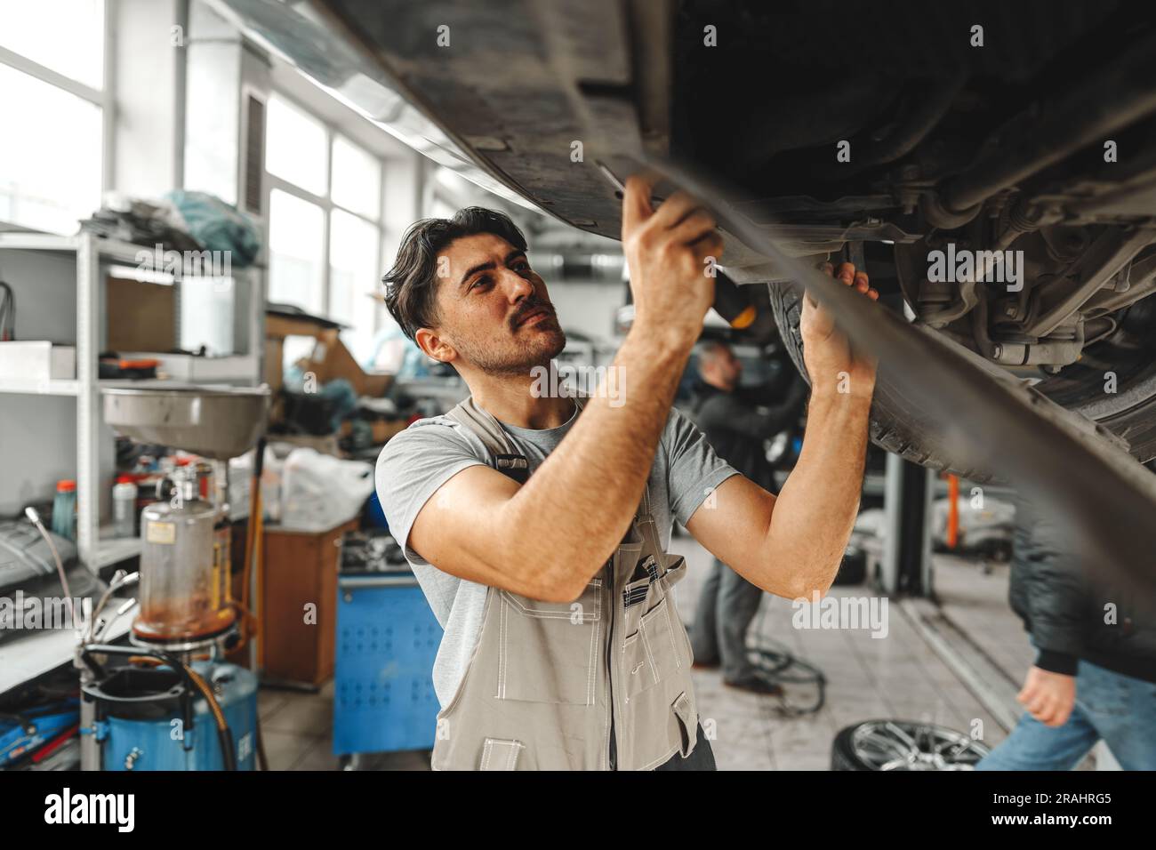 Workman mechanic working under car in auto repair shop Stock Photo - Alamy