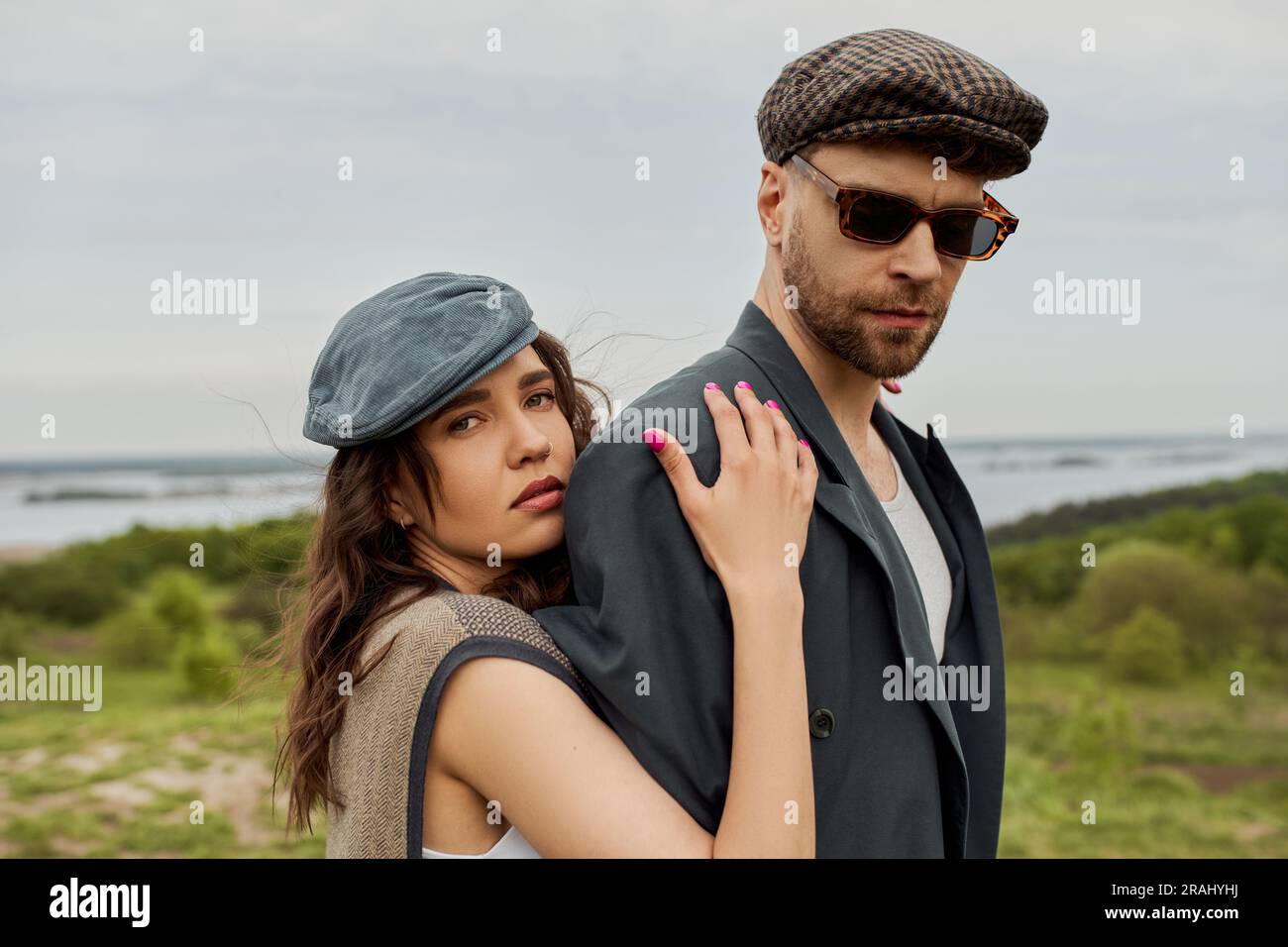 Portrait of trendy brunette woman in newsboy cap and vest hugging ...