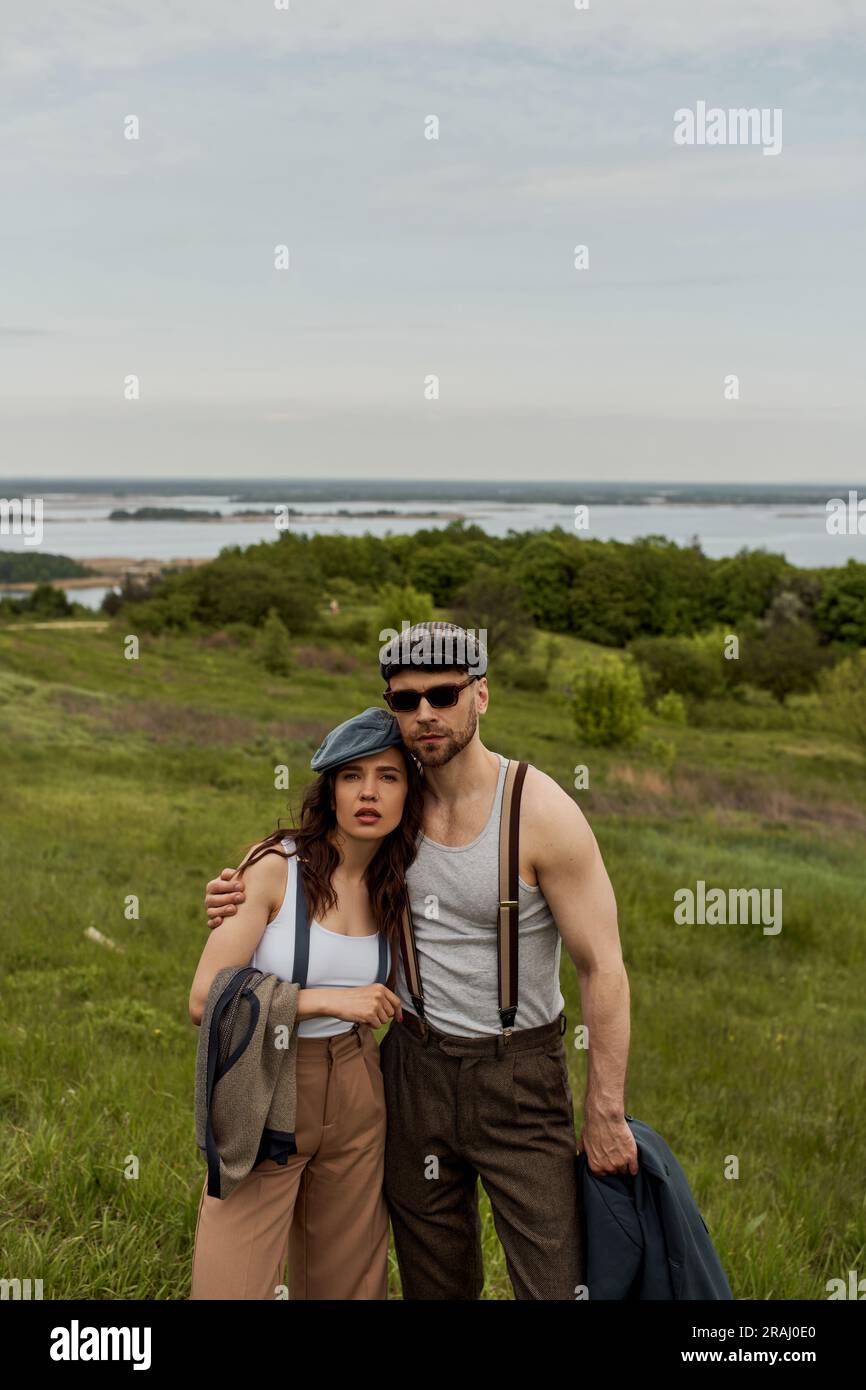 Fashionable romantic couple in newsboy caps and suspenders holding ...