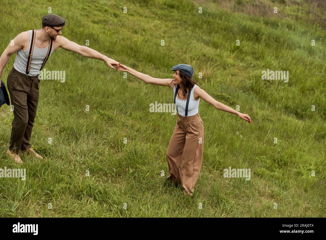 Side view of positive and fashionable couple in newsboy caps and ...
