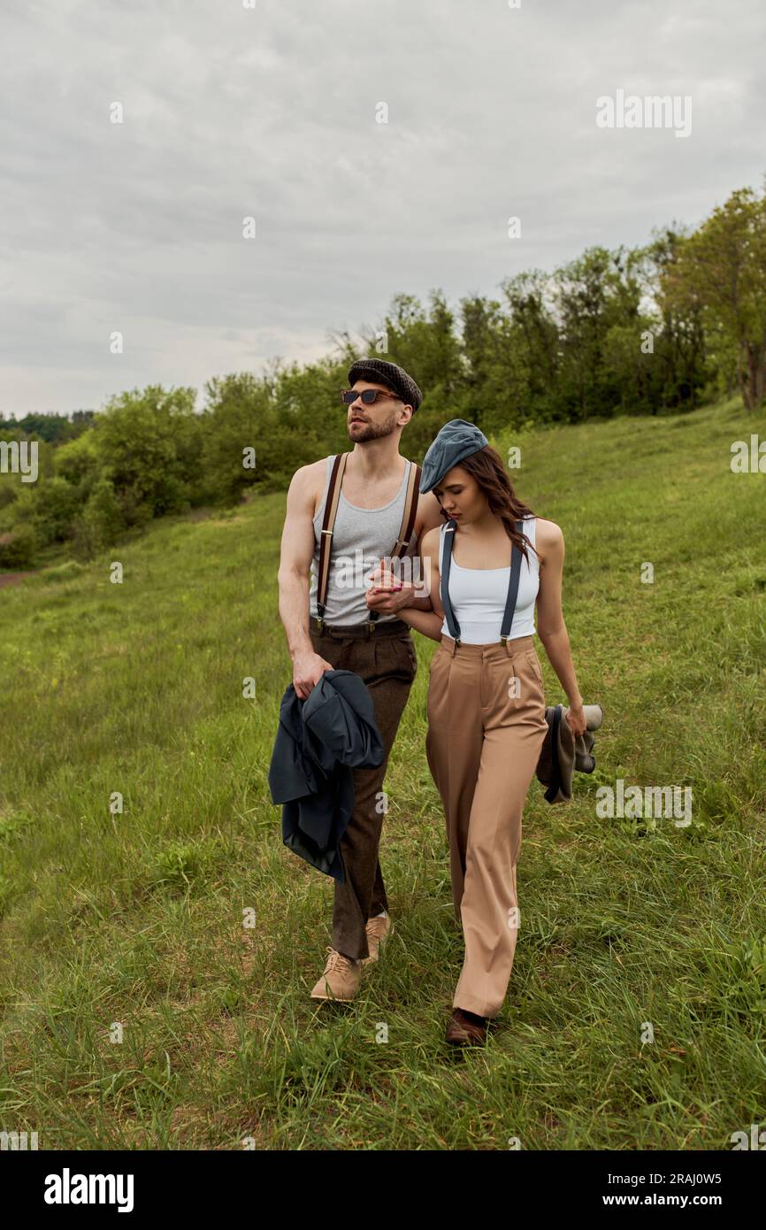 Fashionable man in sunglasses and newsboy cap holding hand of ...