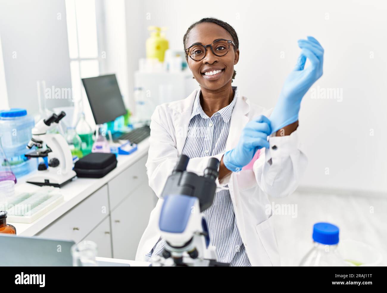 African american woman scientist smiling confident wearing gloves at ...
