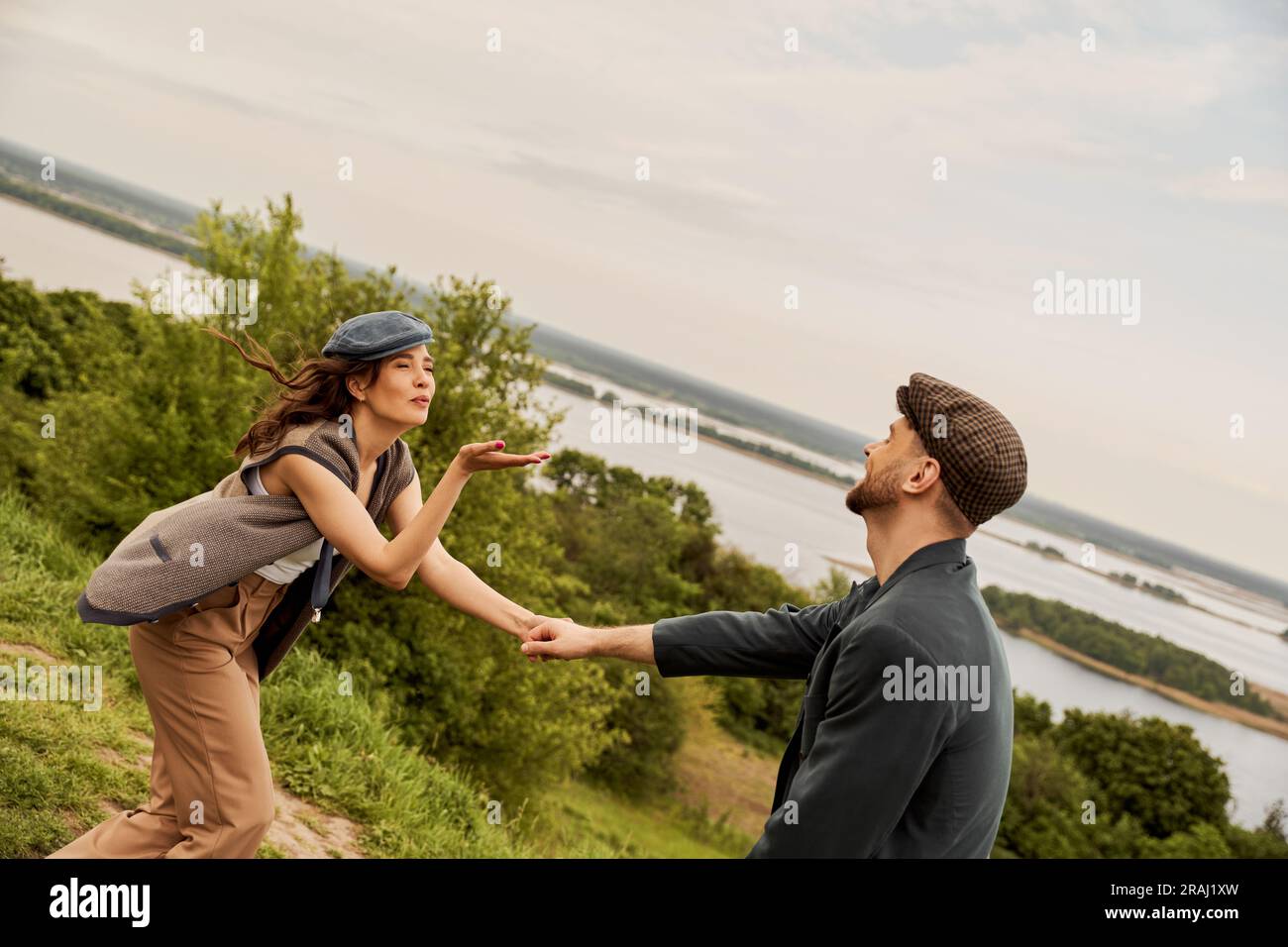 Fashionable brunette woman in newsboy cap and vest blowing air kiss and ...