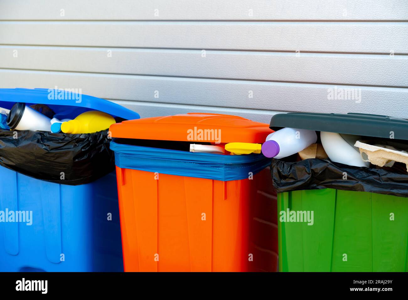 Three trash containers full of garbage near the building Stock Photo