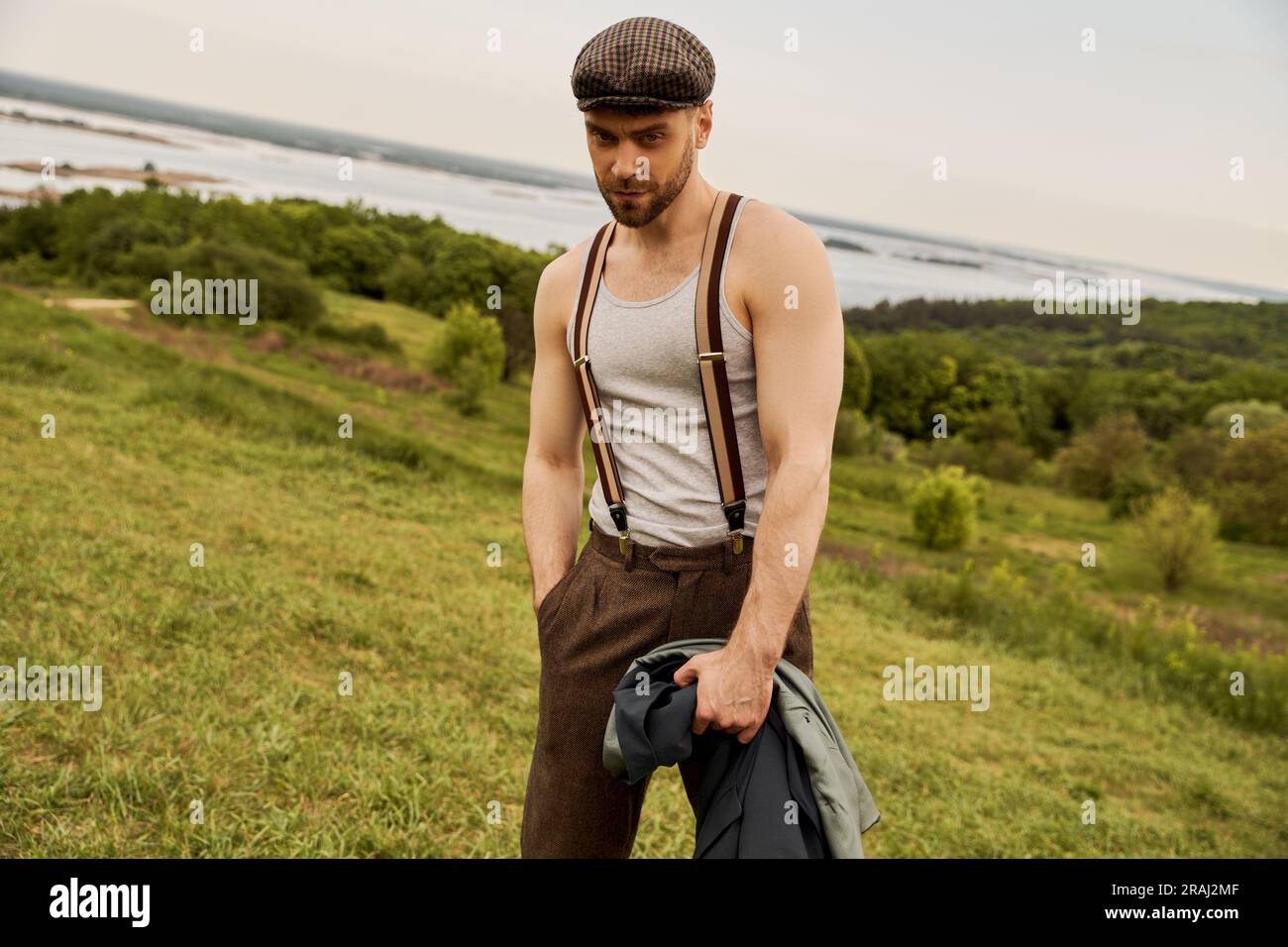 Stylish bearded man in newsboy cap and suspenders holding hand in ...