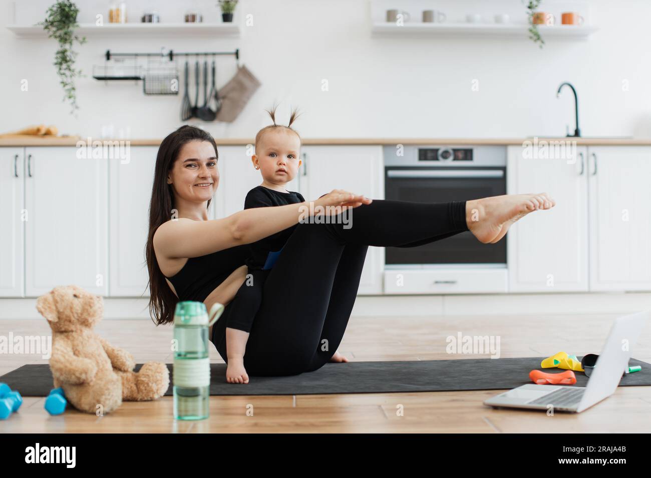 https://c8.alamy.com/comp/2RAJA4B/cheerful-young-lady-in-sportswear-holding-boat-pose-with-cute-baby-girl-on-laps-in-modern-apartment-sporty-adult-mom-doing-baby-yoga-with-little-daughter-using-online-video-on-laptop-at-home-2RAJA4B.jpg