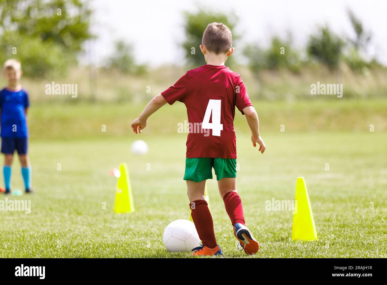 Kids running with soccer balls slalom drill between training yellow