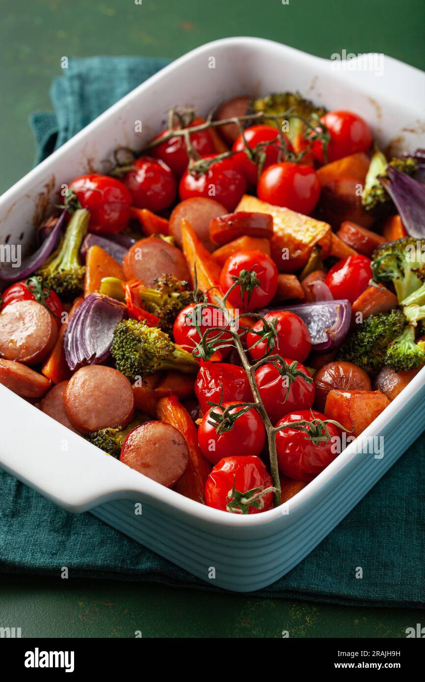oven baked vegetables and sausages, healthy lunch, sweet potato onion tomato broccoli Stock