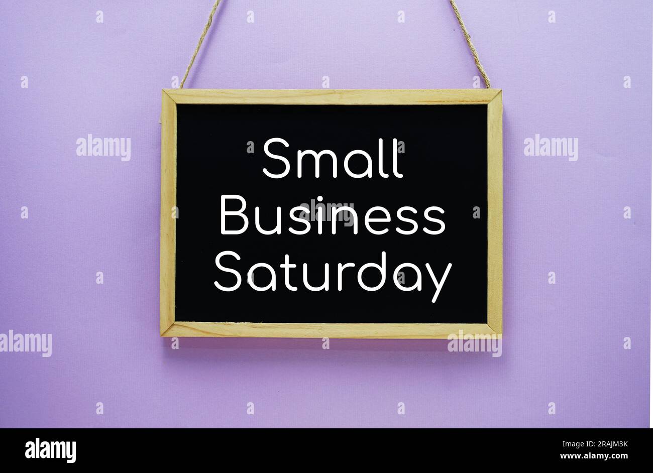 Small Business Saturday typography text on wooden blackboard hanging on purple background Stock Photo