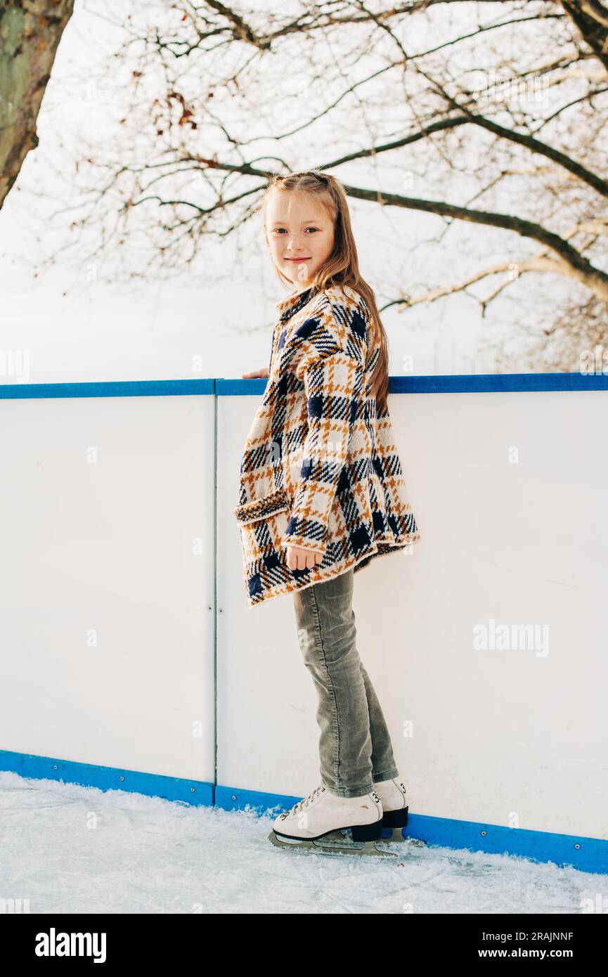 Outdoor portrait of cute little girl spending time on skating rink, winter fun for children Stock Photo