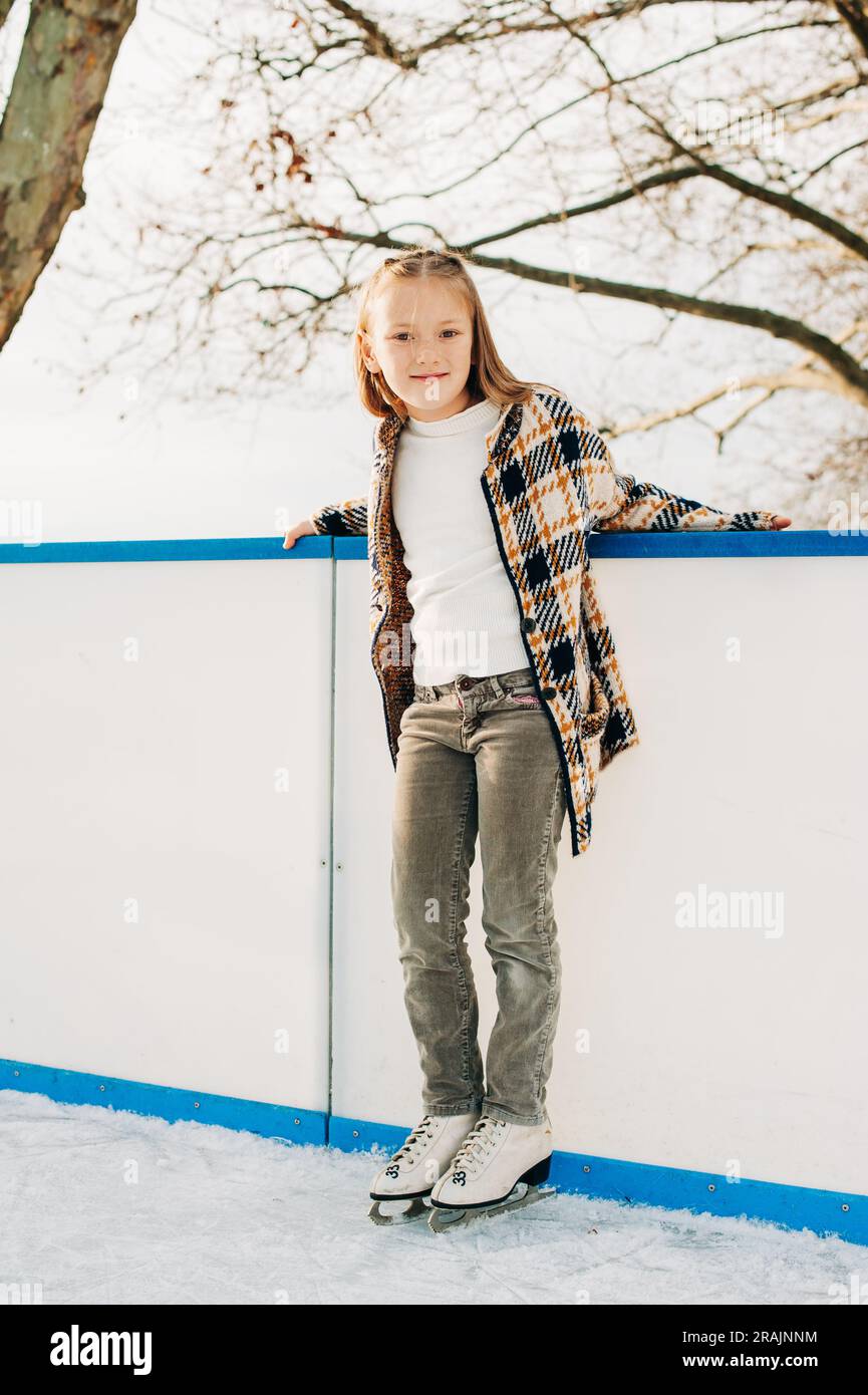 Outdoor portrait of cute little girl spending time on skating rink, winter fun for children Stock Photo