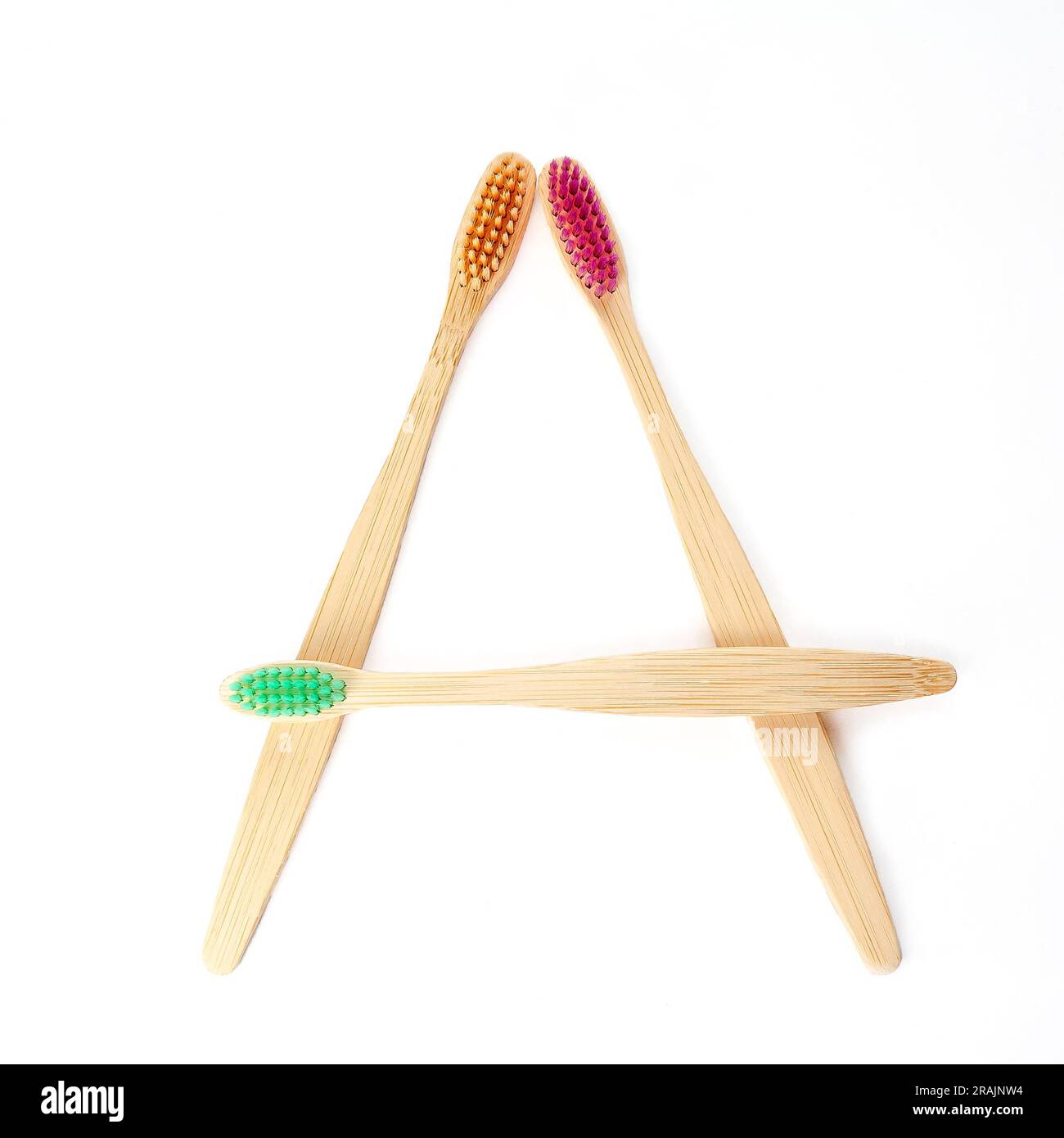 Three multicolored bamboo toothbrushes isolated on a white background. square frame layout. Oral hygiene. Environmentally friendly product. Recyclable Stock Photo