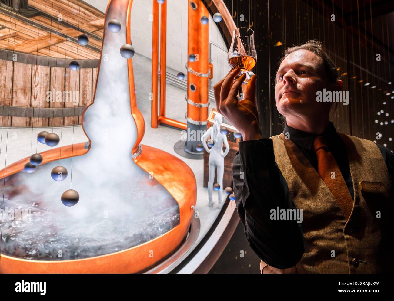 Tour guide with glass of whisky at immersive visitor media image projection about whisky brewing