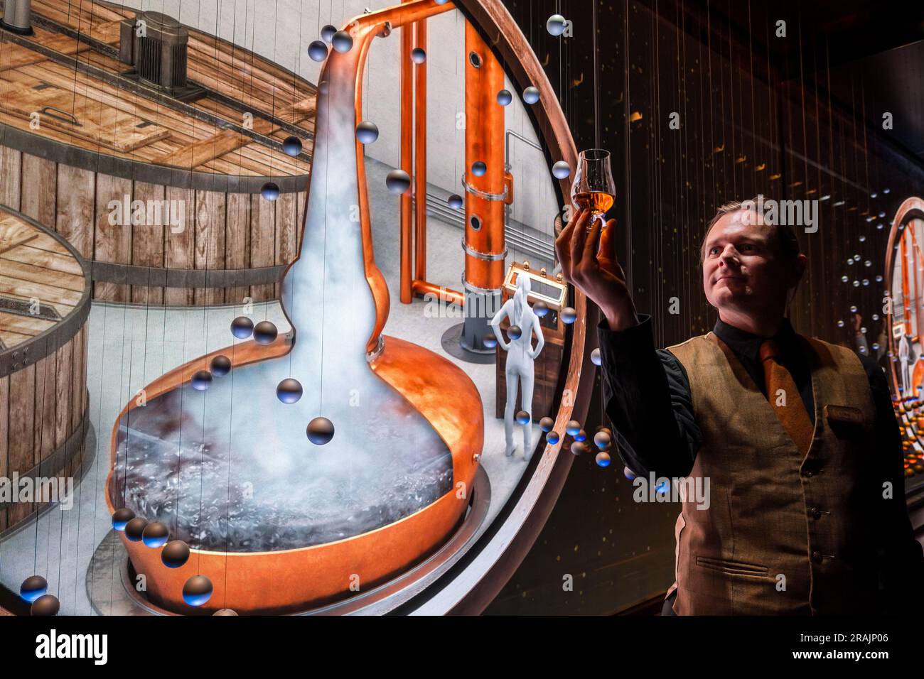 Tour guide with glass of whisky at immersive visitor media image projection about whisky brewing