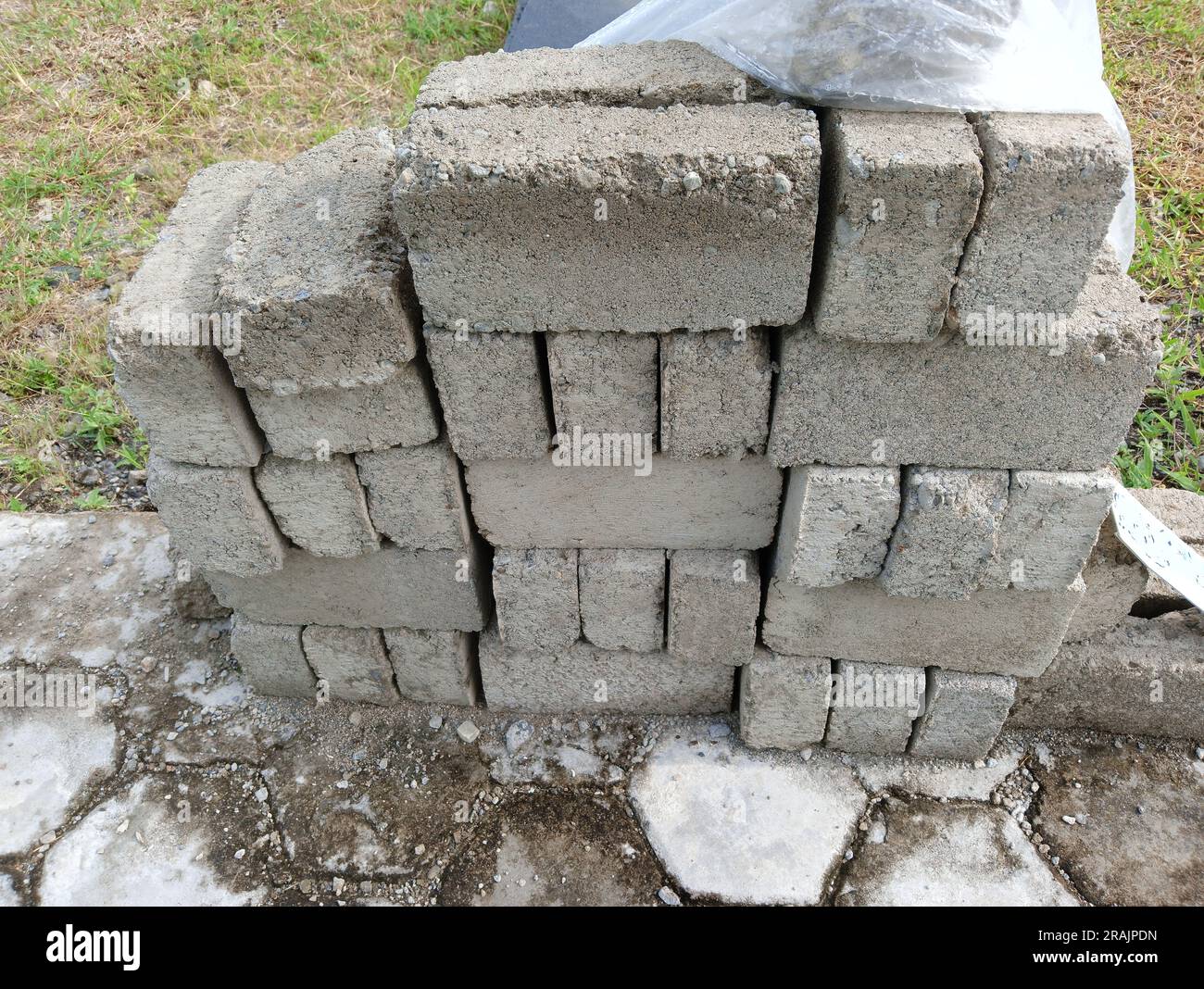 Stack Masonry Stacked concrete building blocks on a hexagonal paving stone surface in ...