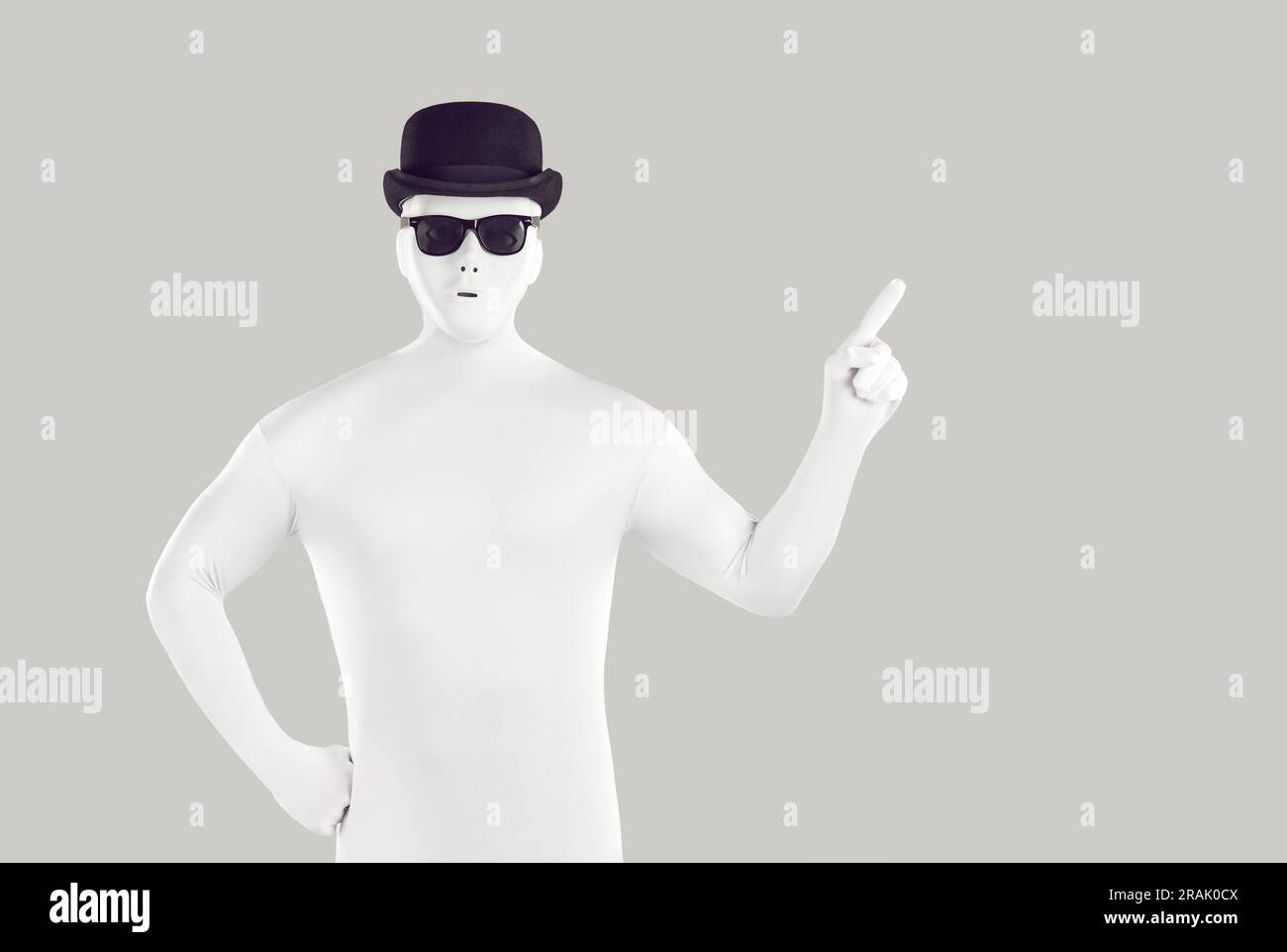 Disguised man dressed in white bodysuit pointing to side with forefinger Stock Photo