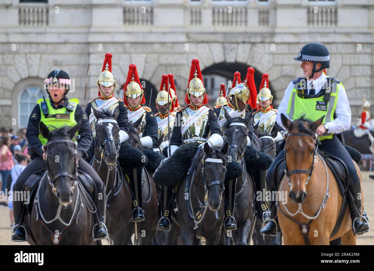 London, UK. Member of the Household Cavalry (Blues and Royals) escorted by mounted police from Horse Guards Parade after the daily Changing of the .. Stock Photo