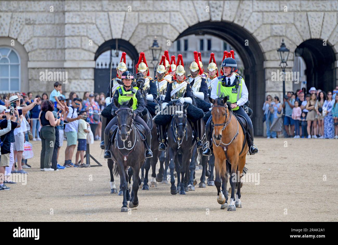 London, UK. Member of the Household Cavalry (Blues and Royals) escorted by mounted police from Horse Guards Parade after the daily Changing of the .. Stock Photo