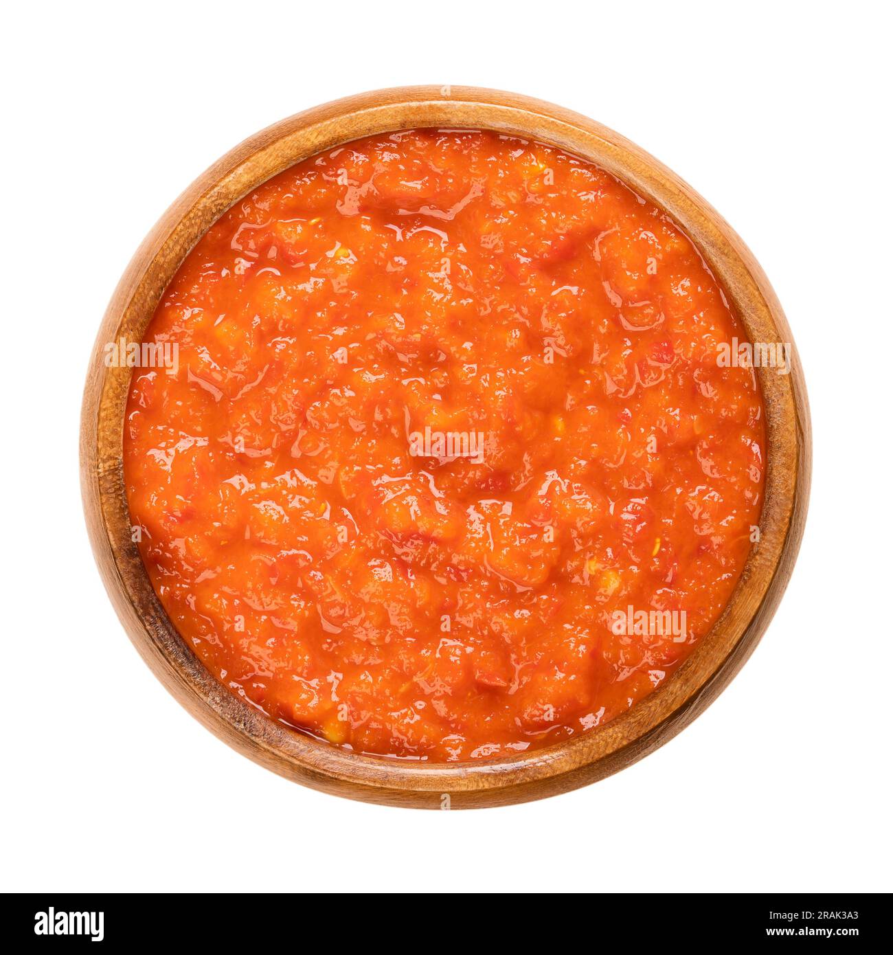 Ajvar, relish made of roasted sweet bell peppers, in a wooden bowl. Condiment, bread spread and side dish, popular in the Balkans. Stock Photo