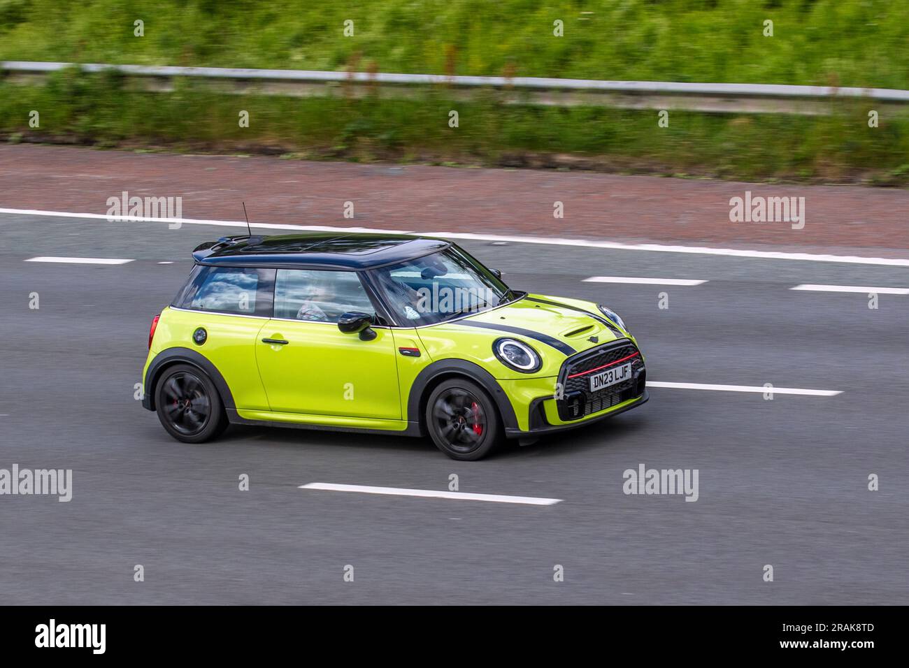 2023 Yellow Mini John Cooper Works Auto, Sport Auto Start/Stop Car Hatchback Petrol 1998 cc, 2.0 litre 4-cylinder petrol engine travelling at speed on the M6 motorway in Greater Manchester, UK Stock Photo