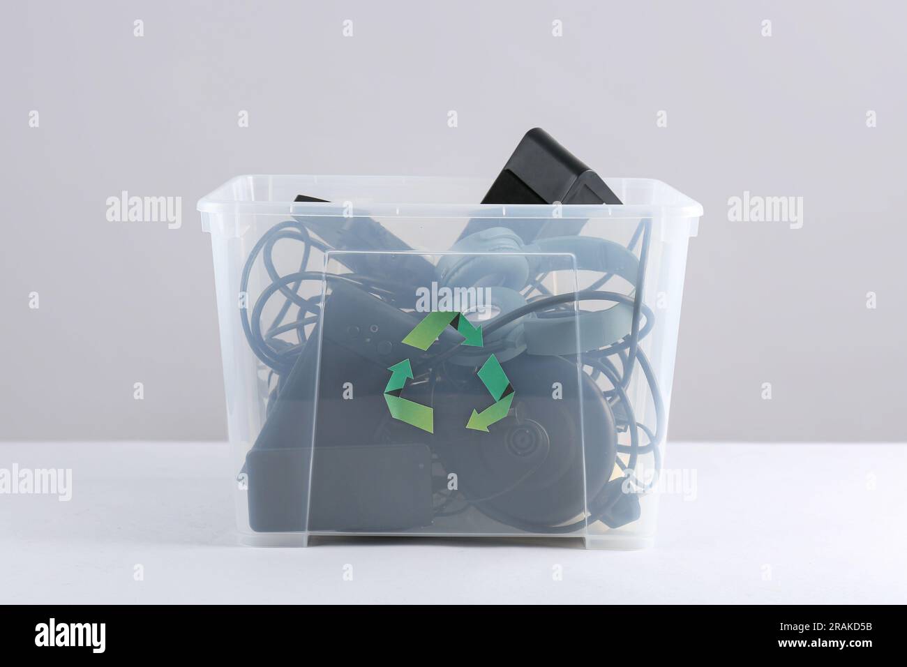 Recycle bin with different household appliances on grey background