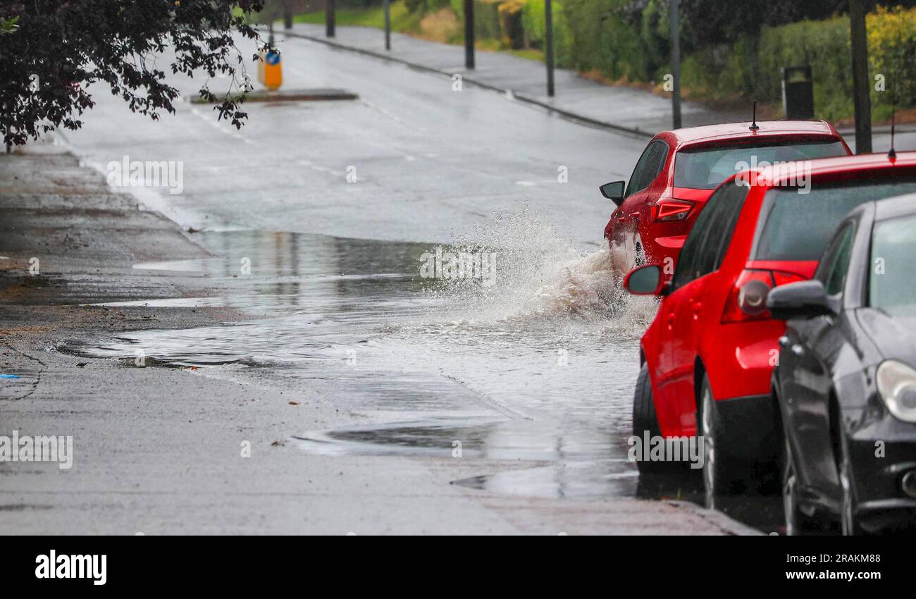 Lurgan, County Armagh, Northern Ireland, UK. 04 Jul 2023. UK weather - an afternoon of slow moving heavy showers. The rain, torrential at times caused localised flooding where drains were overwhelmed - vehicular traffic negotiating  flooding on the main road into Lurgan from the M1 motorway. Credit: CAZIMB/Alamy Live News. Stock Photo