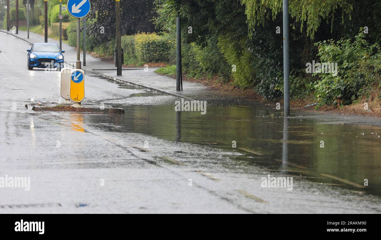 Lurgan, County Armagh, Northern Ireland, UK. 04 Jul 2023. UK weather - an afternoon of slow moving heavy showers. The rain, torrential at times caused localised flooding where drains were overwhelmed - vehicular traffic negotiating  flooding on the main road into Lurgan from the M1 motorway. Credit: CAZIMB/Alamy Live News. Stock Photo