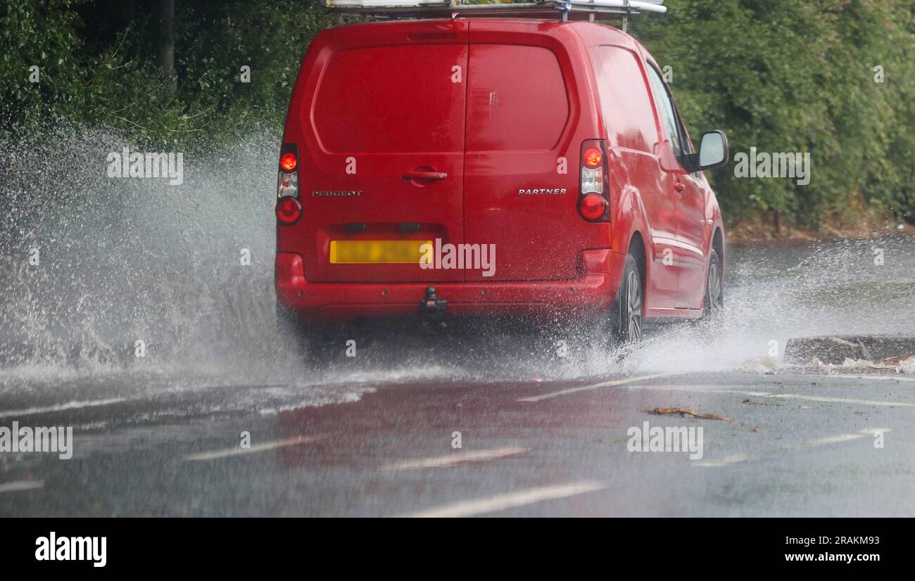 Lurgan, County Armagh, Northern Ireland, UK. 04 Jul 2023. UK weather - an afternoon of slow moving heavy showers. The rain, torrential at times caused localised flooding where drains were overwhelmed - vehicular traffic negotiating  flooding on the main road into Lurgan from the M1 motorway. Credit: CAZIMB/Alamy Live News. Stock Photo