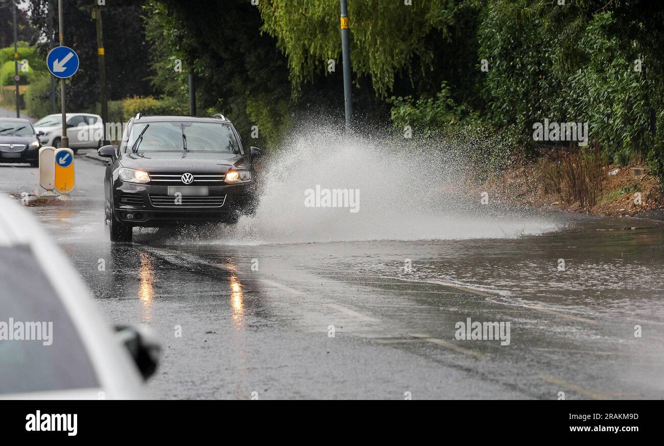 Lurgan, County Armagh, Northern Ireland, UK. 04 Jul 2023. UK weather - an afternoon of slow moving heavy showers. The rain, torrential at times caused localised flooding where drains were overwhelmed - vehicular traffic negotiating  flooding on the main road into Lurgan from the M1 motorway. Credit: CAZIMB/Alamy Live News. Stock Photo