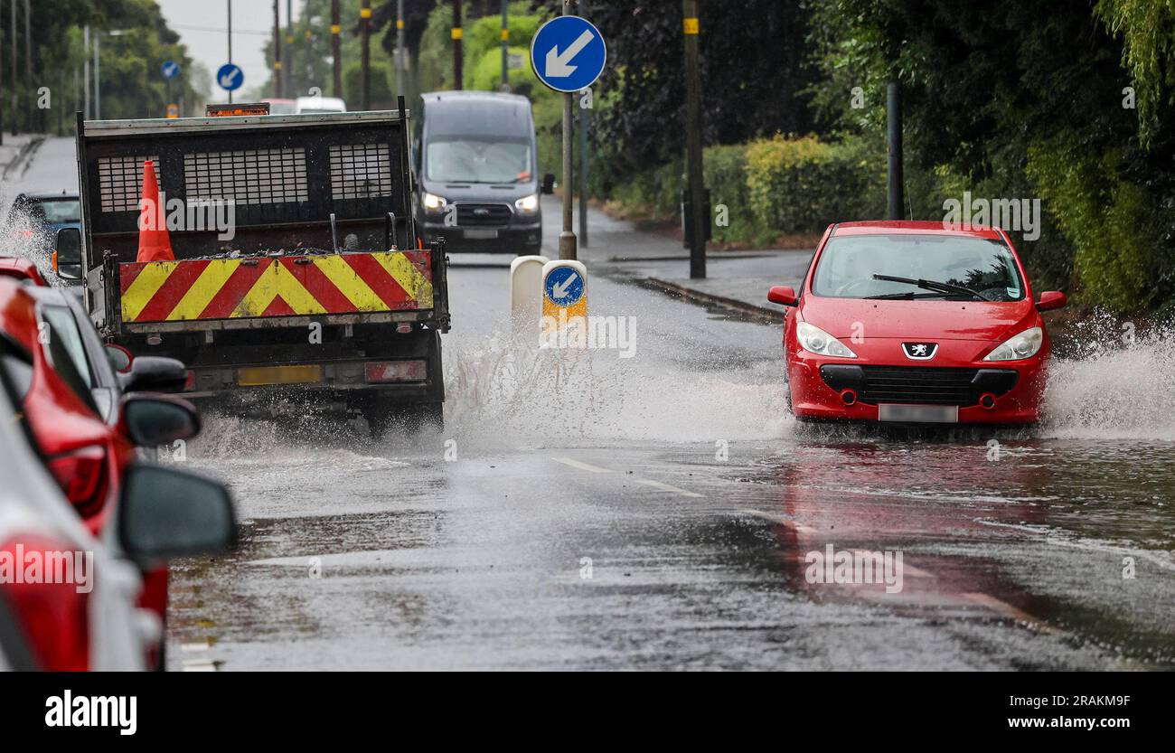 Lurgan, County Armagh, Northern Ireland, UK. 04 Jul 2023. UK weather - an afternoon of slow moving heavy showers. The rain, torrential at times caused localised flooding where drains were overwhelmed - vehicular traffic negotiating  flooding on the main road into Lurgan from the M1 motorway. Credit: CAZIMB/Alamy Live News. Stock Photo