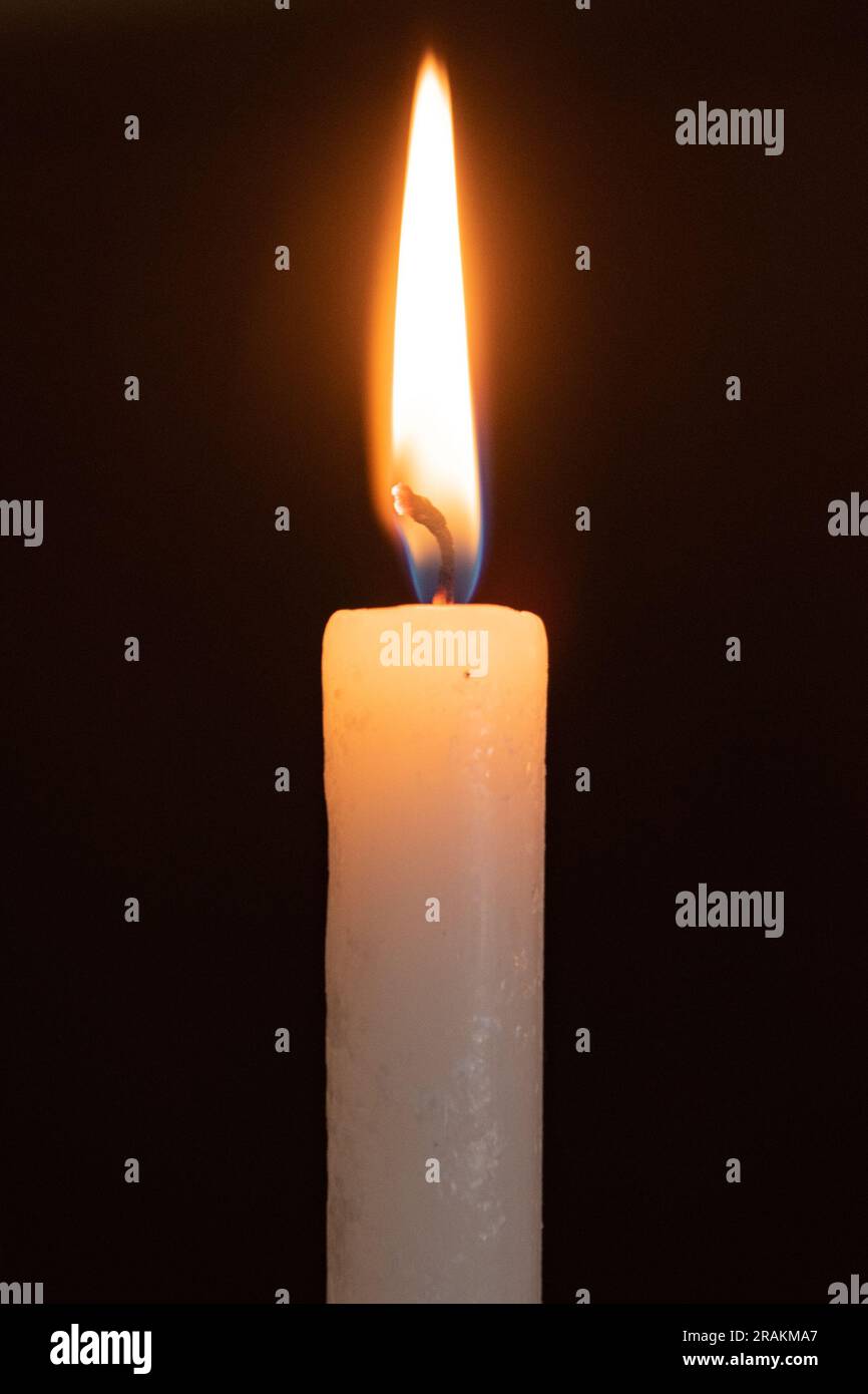 Single burning candle in the foreground Stock Photo