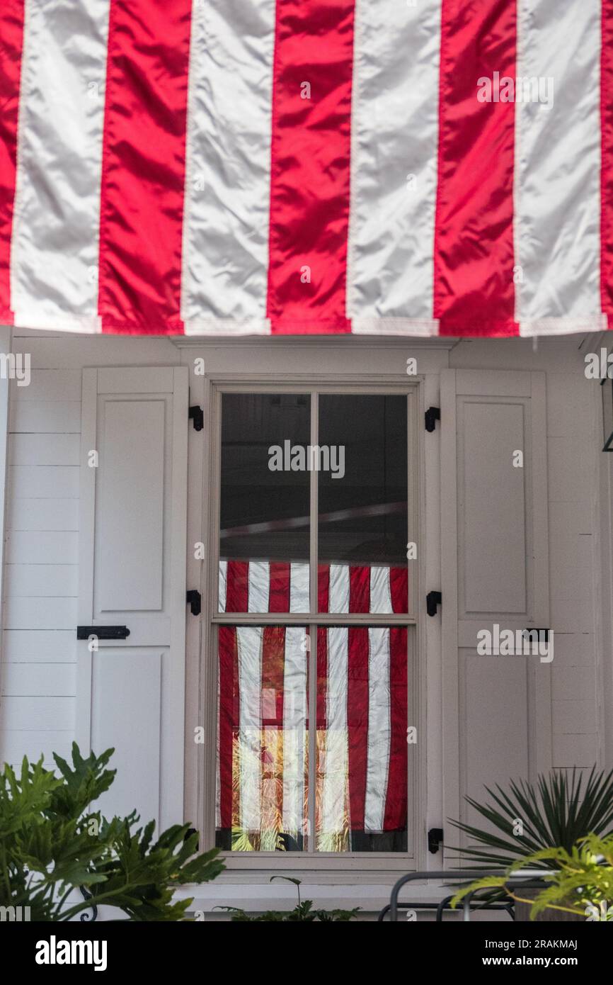 An American flag is reflected in the window of a Charleston single low country style home honoring Independence Day at the I’on Community, July 4, 2021 in Mt Pleasant, South Carolina. Stock Photo