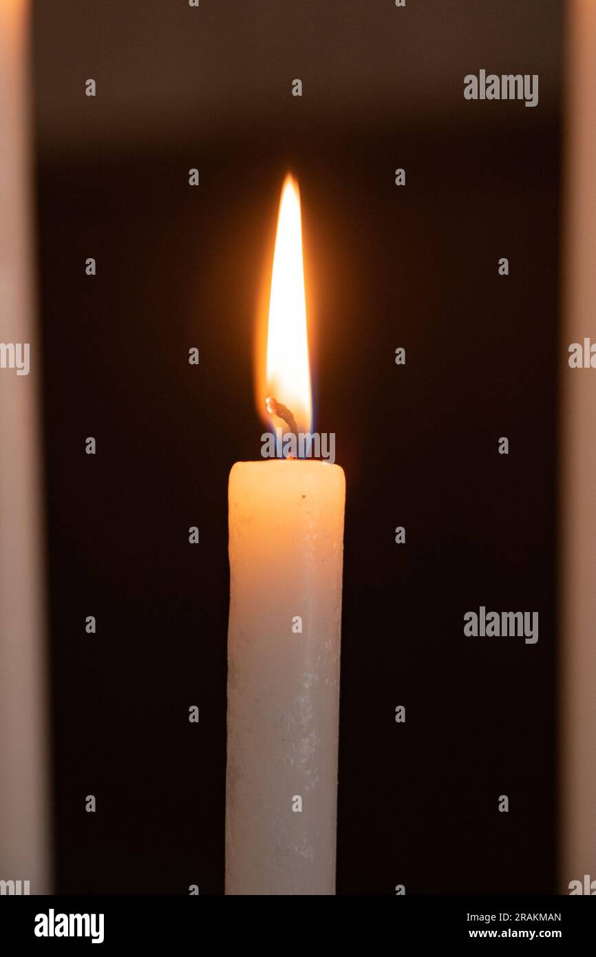 Single burning candle in the foreground Stock Photo