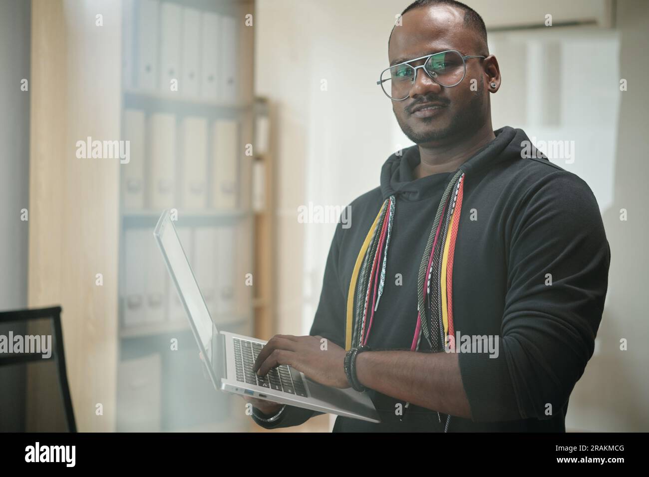 Portrait of software developer in hoodie programming on laptop Stock Photo