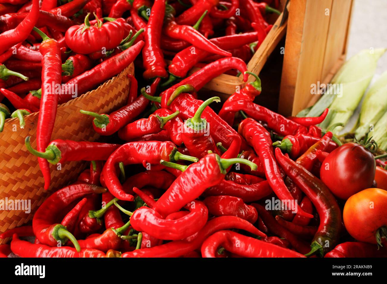A view of several red cayenne chili peppers spilling out of a basket ...