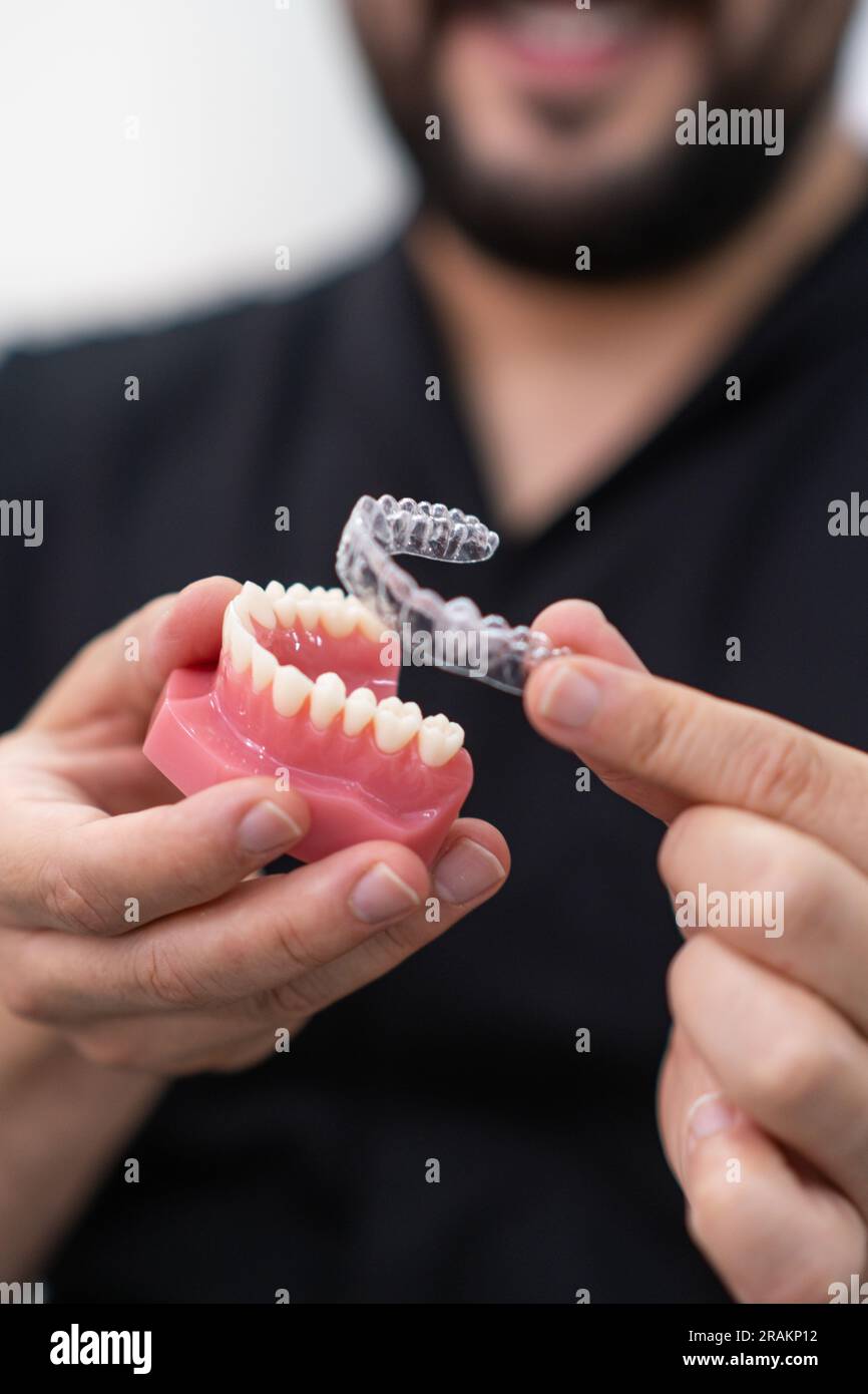 Doctor demonstrating clear aligners installation on artificial lower