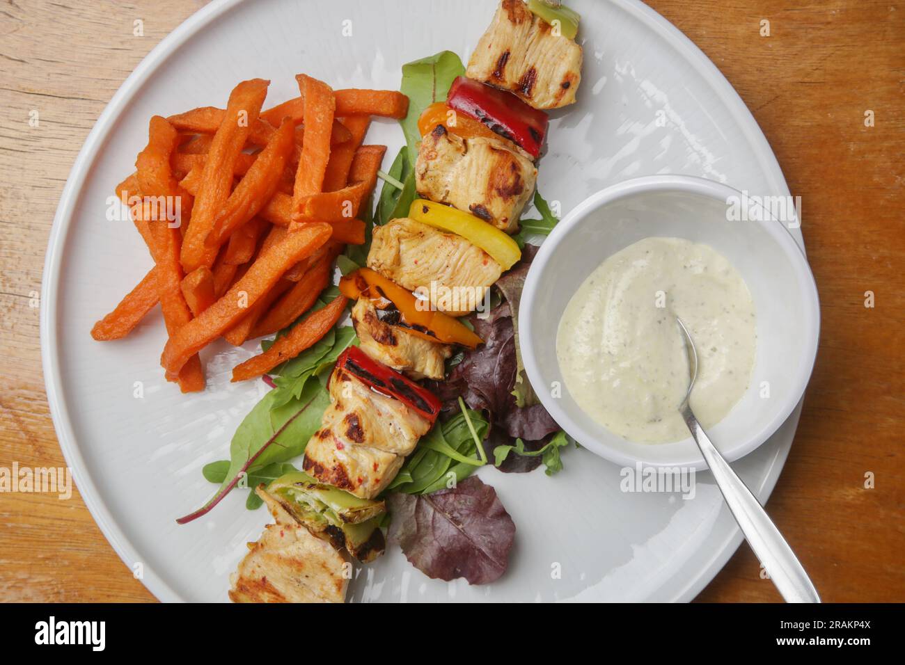 Greek souvlaki, sweet potatoe and tzatziki yogurt dip served on the plate in the restaurant Stock Photo