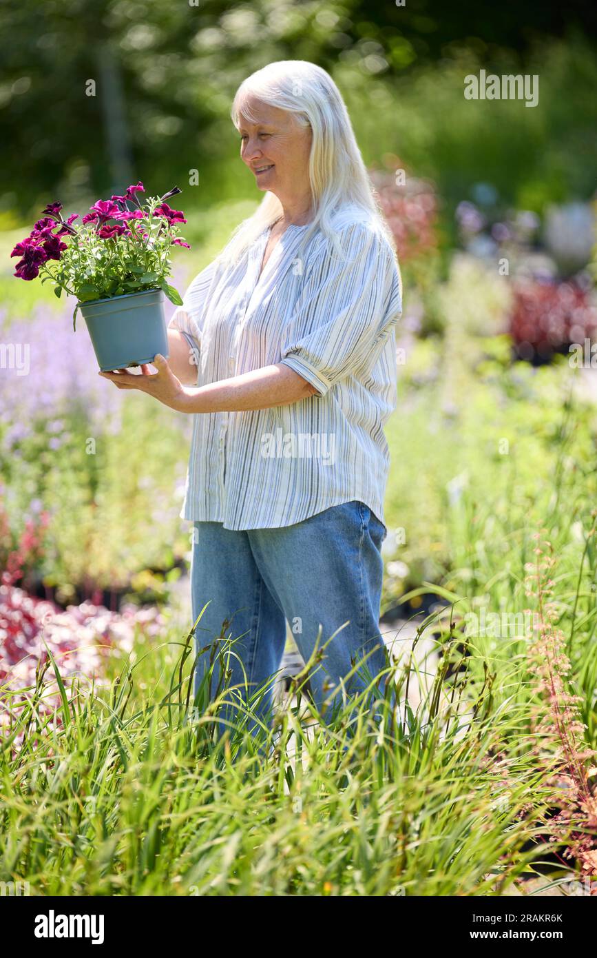 Senior Female Customer In Garden Centre Choosing Plant Stock Photo