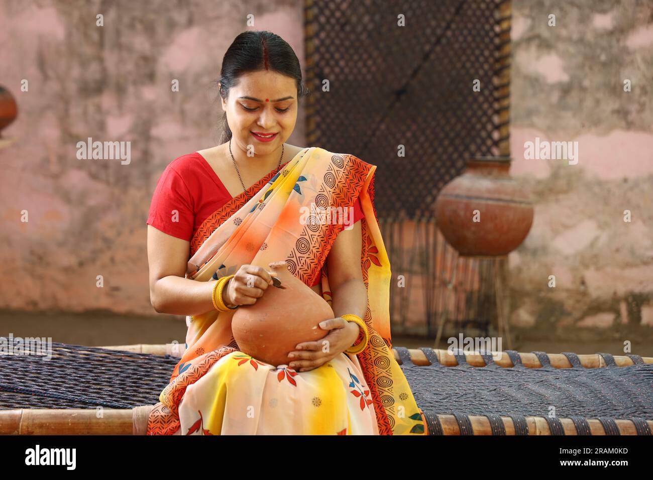 Happy rural Indian women in saree with the Piggy Bank in hand. Aspirational woman showing her love towards saved money for her future for going abroad. Stock Photo