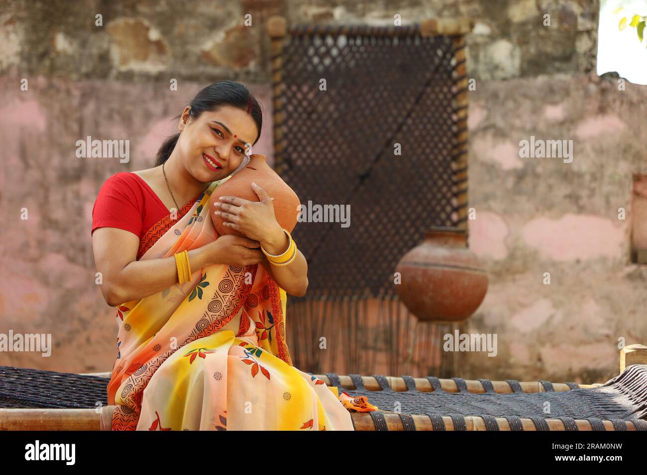 Happy rural Indian women in saree with the Piggy Bank in hand. Aspirational woman showing her love towards saved money for her future for going abroad. Stock Photo