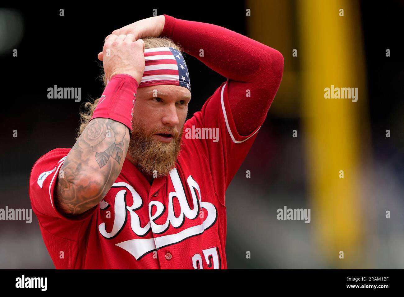Cincinnati Reds' Jake Fraley adjusts a headband depicting the American flag  as he walks on the field between innings of a baseball game against the  Washington Nationals, Tuesday, July 4, 2023, in
