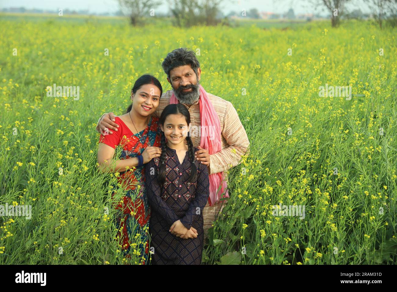 Happy Indian farmers family standing in mustard field in day time ...