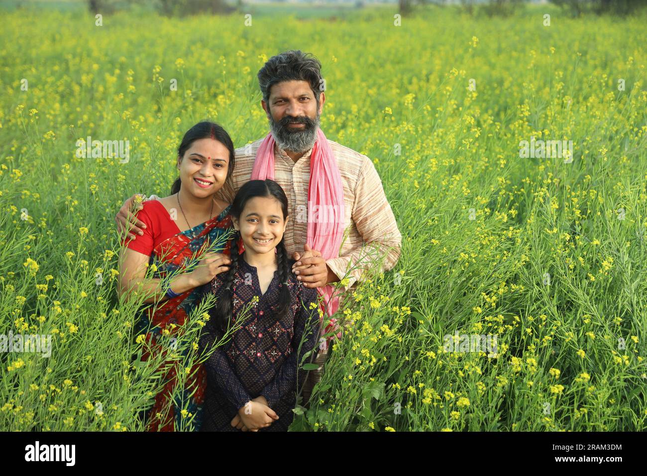 Happy Indian farmers family standing in mustard field in day time ...