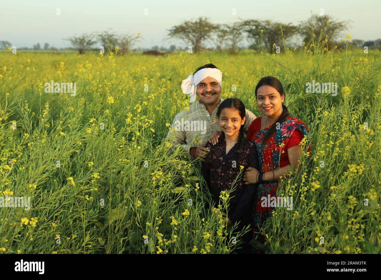 Happy Indian farmers family standing in mustard field in day time ...