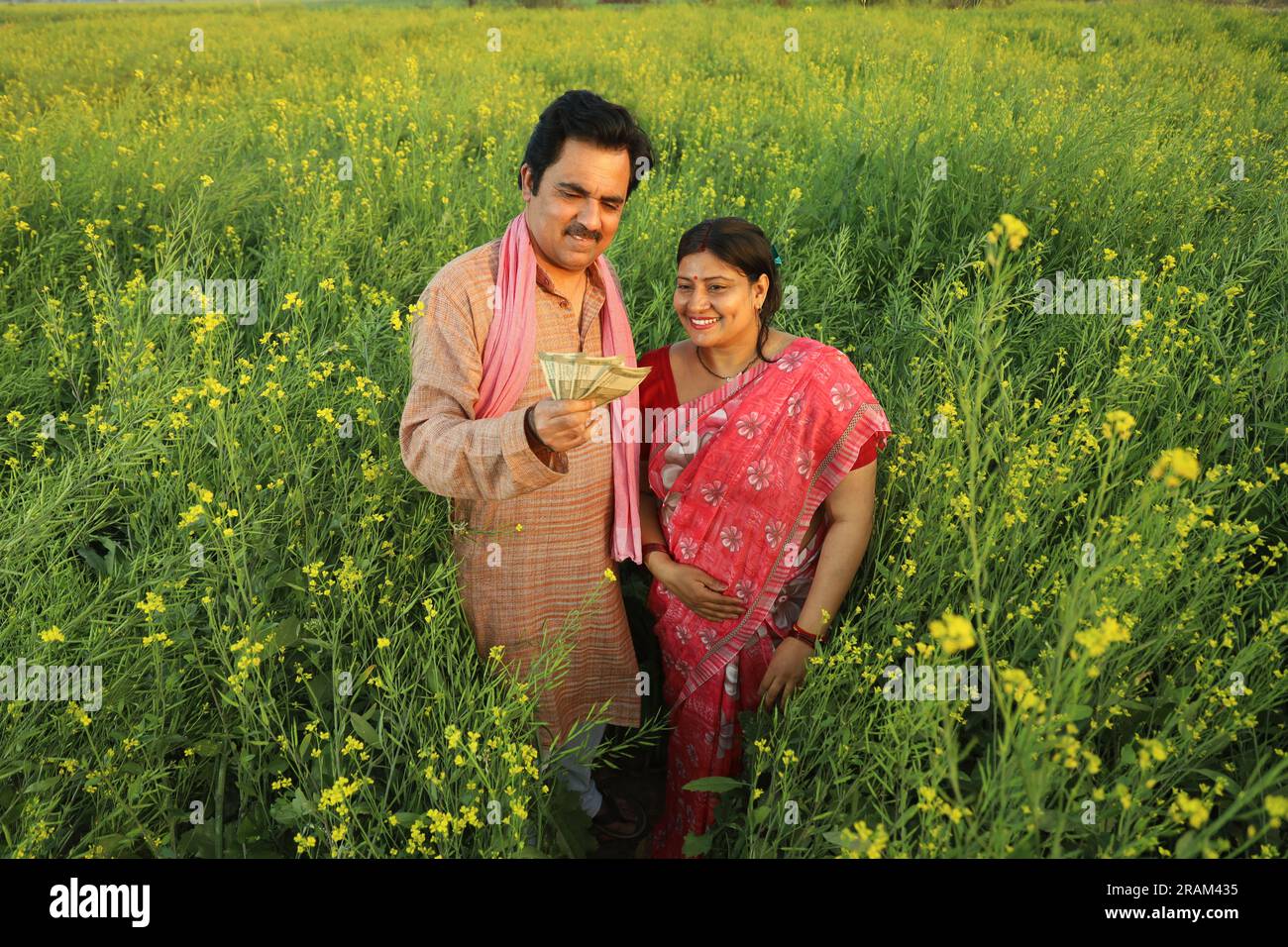 Happy Indian farmer couple standing in mustard field enjoying the ...