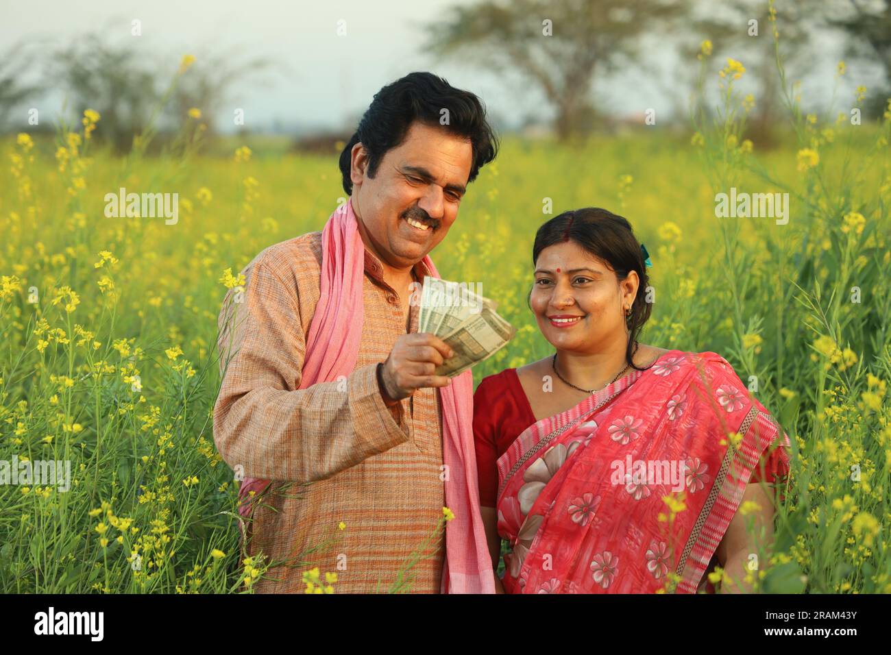 Happy Indian farmer couple standing in mustard field enjoying the ...